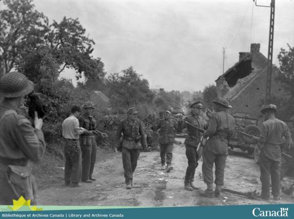 Photo noir et blanc montrant un groupe de soldat allemande avec les mains en l’air et entouré de soldats canadien.