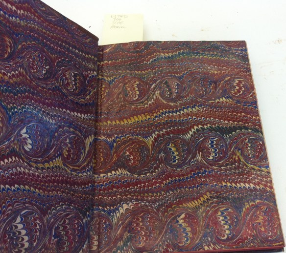 Photographie couleur d’un livre ouvert montrant un somptueux papier marbré servant de page de garde.