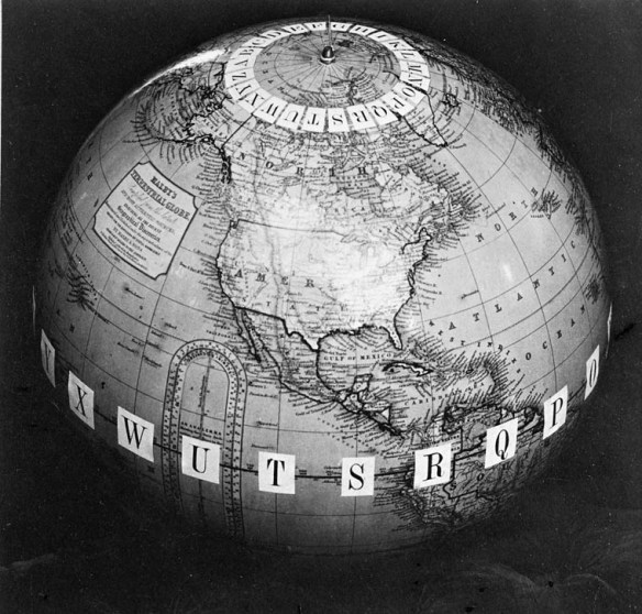 Photographie noir et blanc d’un globe terrestre montrant l’Amérique du Nord, avec des lettres fixées sur chaque méridien, tant autour du pôle Nord que de l’équateur.