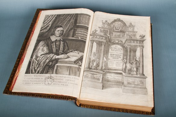 Une photo en couleur montrant un livre ouvert montrant une image d'un homme habillé somptueusement sur la page verso et une frontispice somptueusement illustré sur le recto.