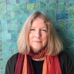 Photographie en couleur d'une femme debout devant un mur turquoise