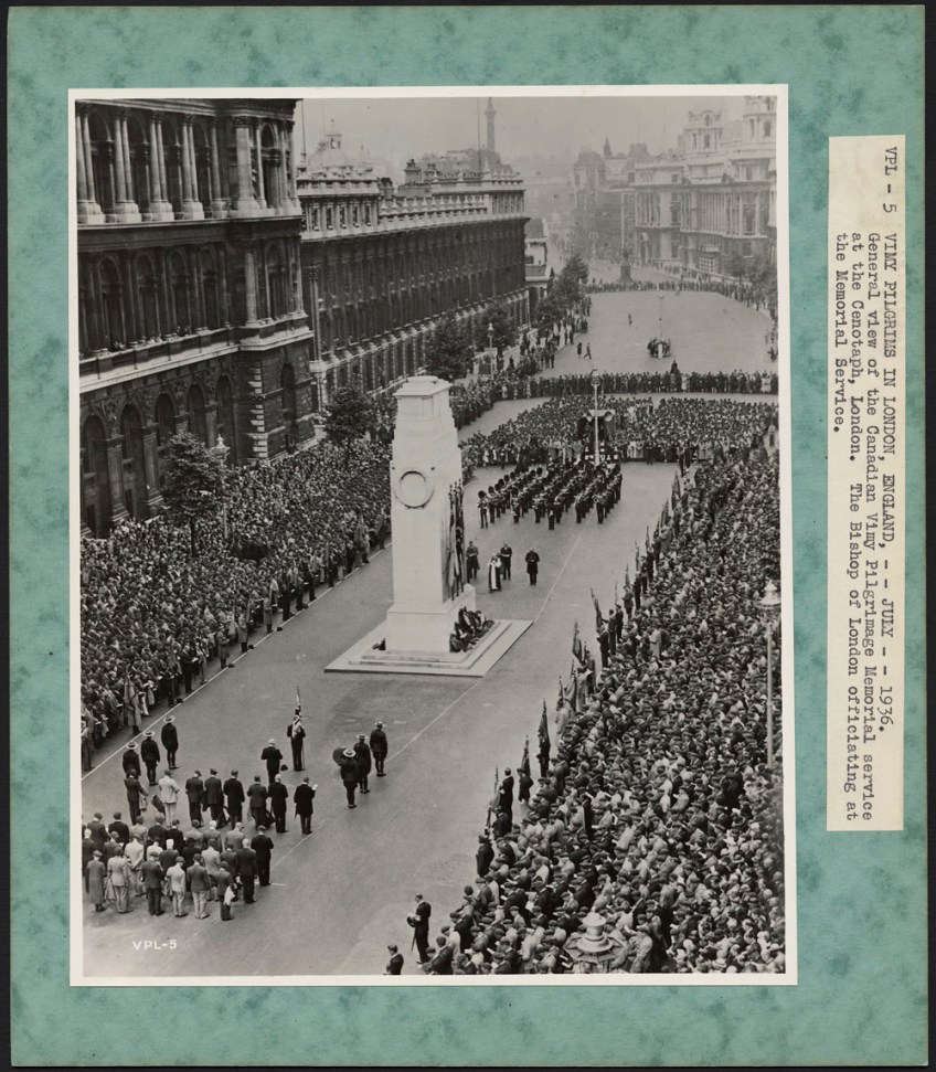 Photographie noir et blanc d’une grande foule sur un trottoir, lors d’une cérémonie. Elle entoure des soldats placés en formation devant un imposant cénotaphe blanc.