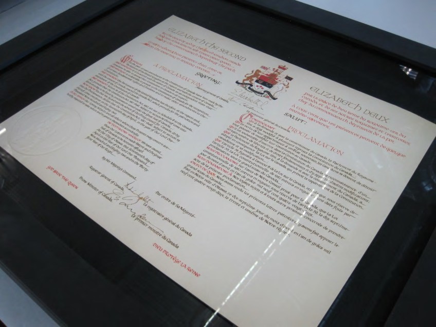 Gros plan du caisson de préservation exposant un exemplaire de la proclamation, sous verre dans un cadre noir.
