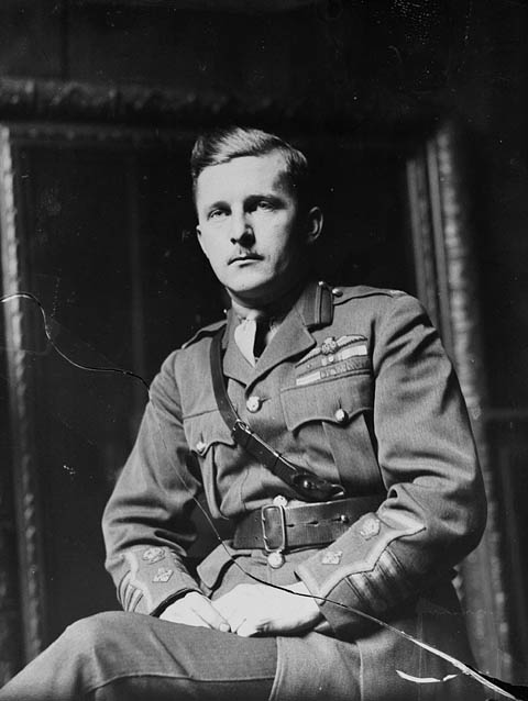Photographie en noir et blanc d’un militaire assis, les mains sur les cuisses. Il porte la ceinture Sam Browne, une large ceinture en cuir munie d’une courroie plus étroite placée en diagonale et qui passe par-dessus l’épaule droite.