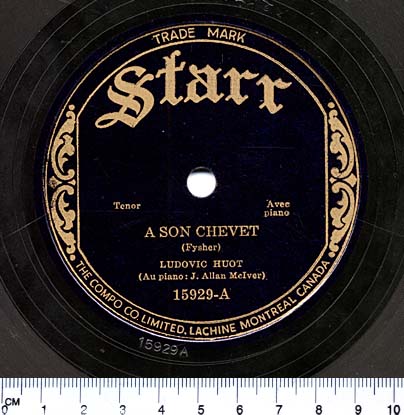 Photographie en couleur d’une étiquette circulaire noire au centre d’un disque 78 tours. En lettres dorées, on peut lire « Starr, Tenor, Avec piano, A SON CHEVET (Fyscher), LUDOVIC HUOT (Au piano : J. Allan McIver). 15929-A ».