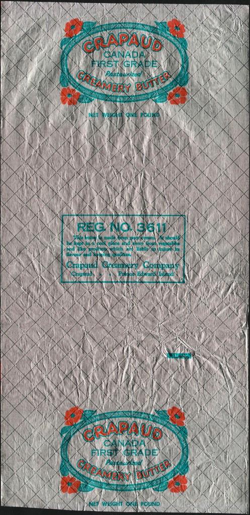 Un emballage de papier métallisé avec le texte suivant: “Crapaud Creamery Butter. Canada First Grade. Pasteurized” (Beurre de crémerie Crapaud. Canada, Première Catégorie. Pasteurisé) Le texte est dans un petit médaillon ovale avec des petites fleurs rouges dans chaque coin.
