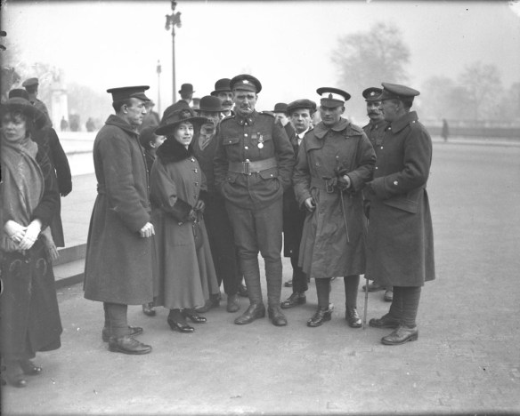 Photographie en noir et blanc d’un groupe de personnes entourant deux soldats.