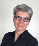 Photo en couleur d'une femme portant des lunettes regardant directement dans la caméra.