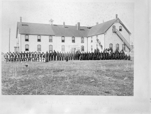 Élèves en uniformes debout devant le pensionnat indien (école des métiers) de Battleford (Saskatchewan), 1895.