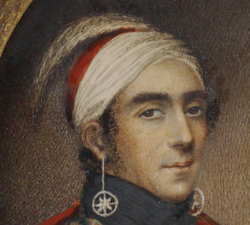 La coiffe de John Norton en détail. Elle est blanche et rouge. Une plume d’autruche y est piquée sur le devant.