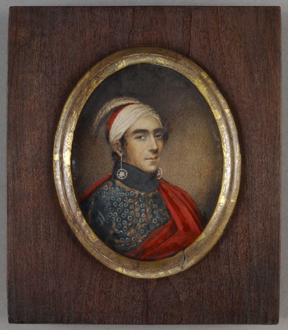 Portrait en miniature ovale du major John Norton, Teyoninhokarawen, portant une coiffe rouge et blanche dans laquelle est piquée une plume d’autruche. Il porte aussi de longues boucles d’oreilles composées d’étoiles encerclées, une chemise à motifs et une cape rouge.