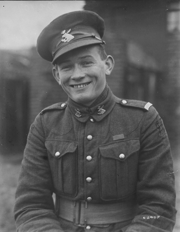 Photo noir et blanc d’un jeune homme souriant, en uniforme, la casquette légèrement de travers.