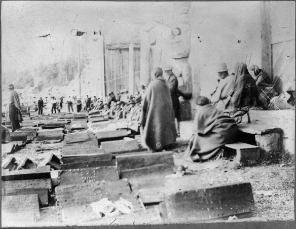 Photo noir et blanc d’un groupe de participants à un potlatch et d’objets devant être donnés.