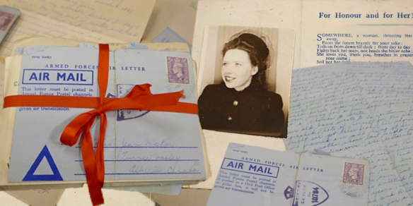 Photographie en couleurs de paquets de lettres, dont un ficelé d’un ruban rouge. Sous les paquets se trouve la photographie d’une jeune femme vêtue d’un manteau et d’un élégant chapeau.