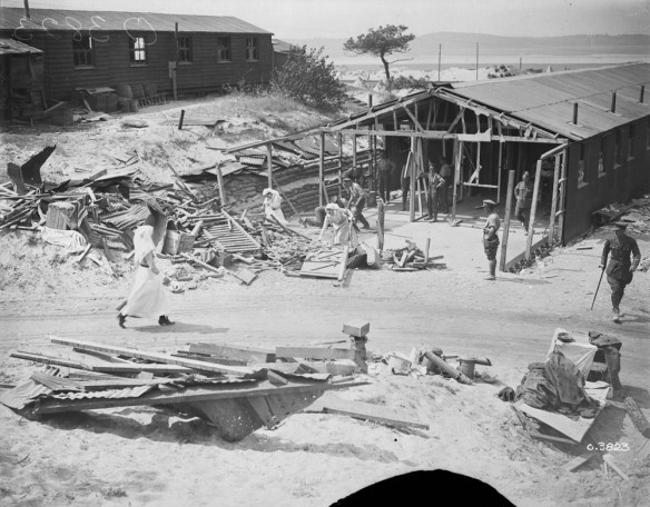 Photo noir et blanc d’infirmières militaires et de soldats en uniforme dégageant les débris d’un hôpital endommagé.