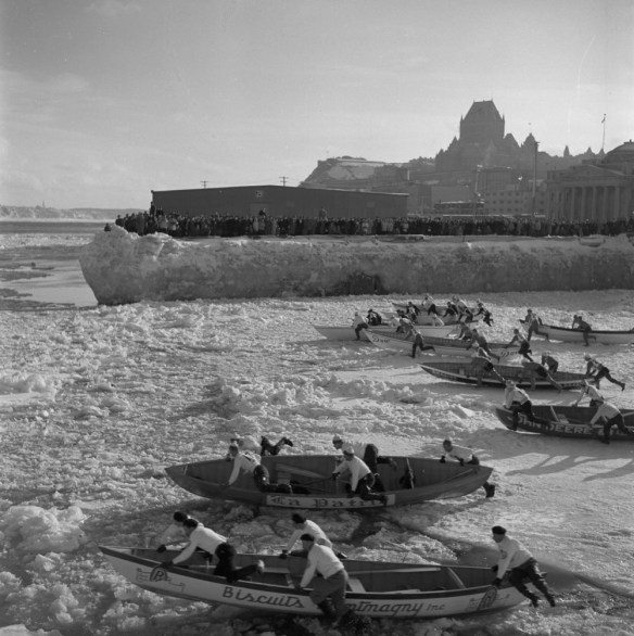 Une photographie noir et blanc de huit équipes poussant leur canot sur les glaces du fleuve en direction de l’eau libre.