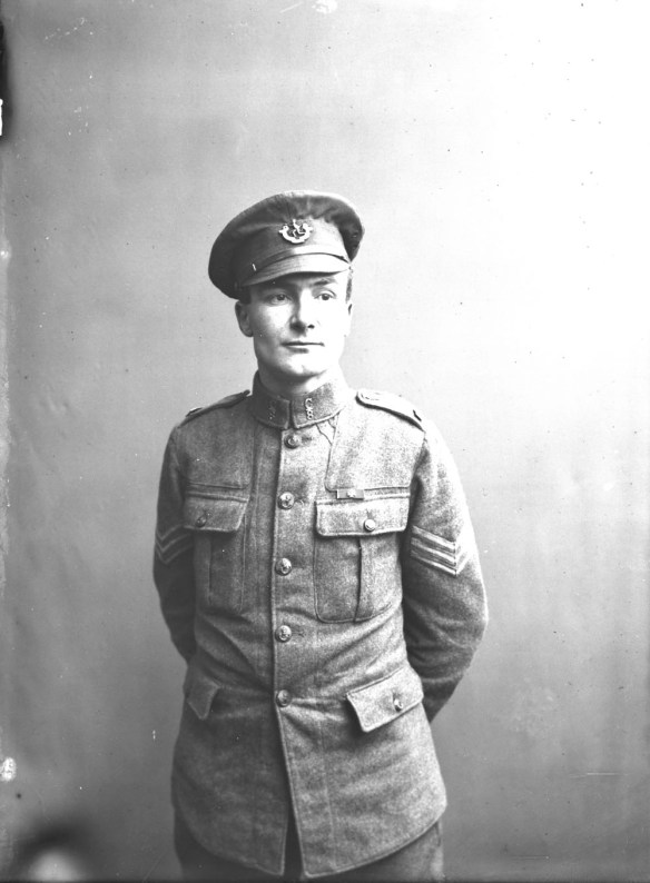 Photo noir et blanc d’un soldat en uniforme, debout, les mains derrière le dos.
