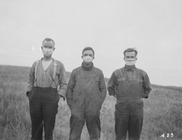 Photo noir et blanc montrant trois hommes portant des masques hygiéniques. 