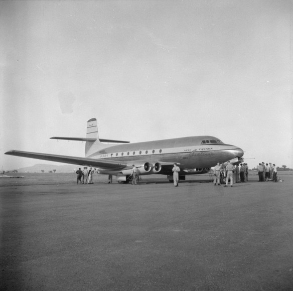 Photo noir et blanc d’un avion sur une piste, entouré de groupes d’hommes.