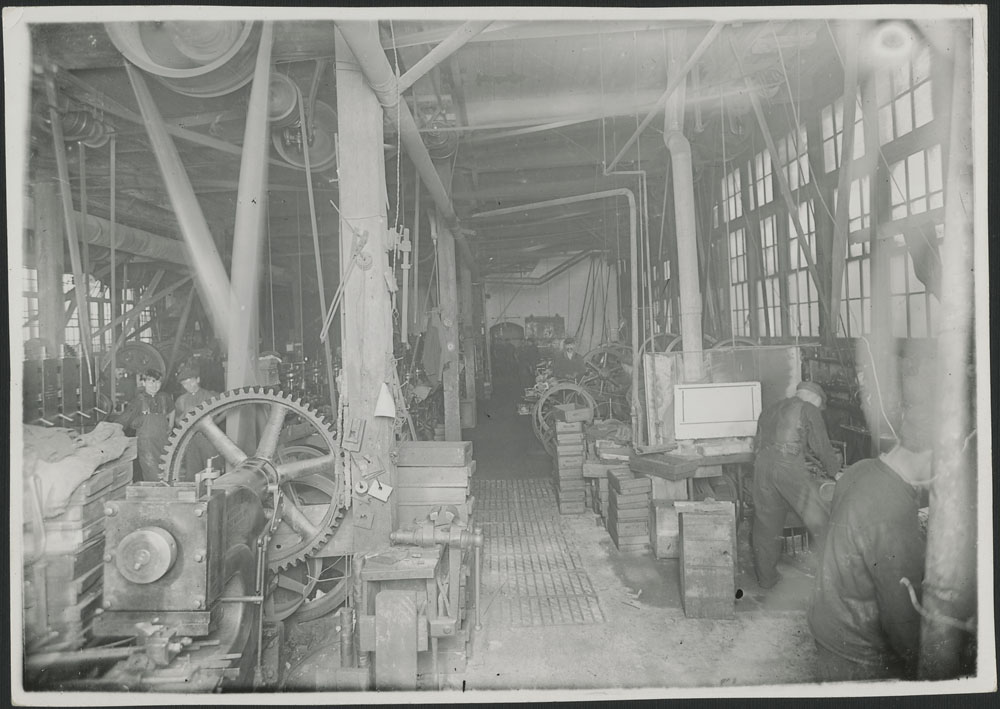 Photographie noir et blanc montrant l’intérieur d’une usine de fabrication de munitions et de fils barbelés, en 1916.