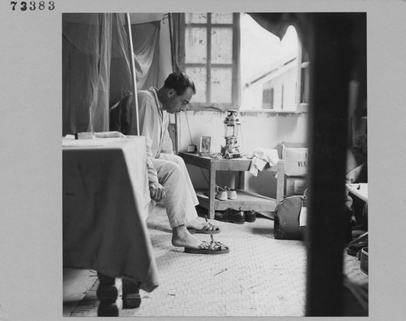 Photo noir et blanc d’un homme mettant ses pantoufles avant de se lever de son lit. 