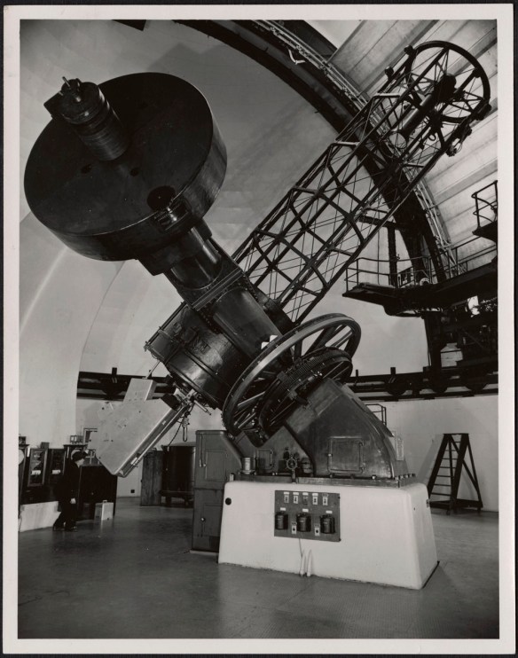 Photographie noir et blanc d’un homme regardant dans l’oculaire du télescope de l’Observatoire fédéral d’astrophysique à Victoria. 