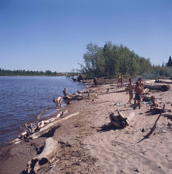 Photo couleur d’un groupe de garçons jouant sur la plage près d’un lac.