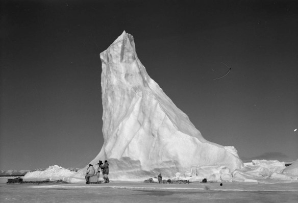 Photo noir et blanc d’un iceberg arrondi avec affleurement en bloc au milieu de l’océan. 