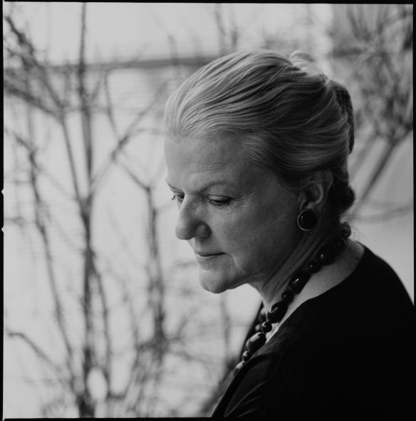 Photographie noir et blanc d’une femme de profil aux cheveux gris portant un collier foncé. 