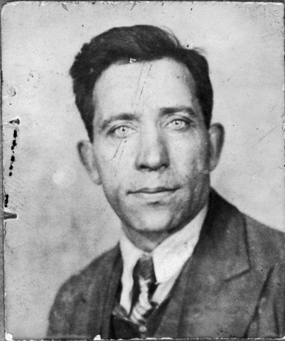 Photographie noir et blanc d’un homme en complet-cravate fixant l’appareil photo. 