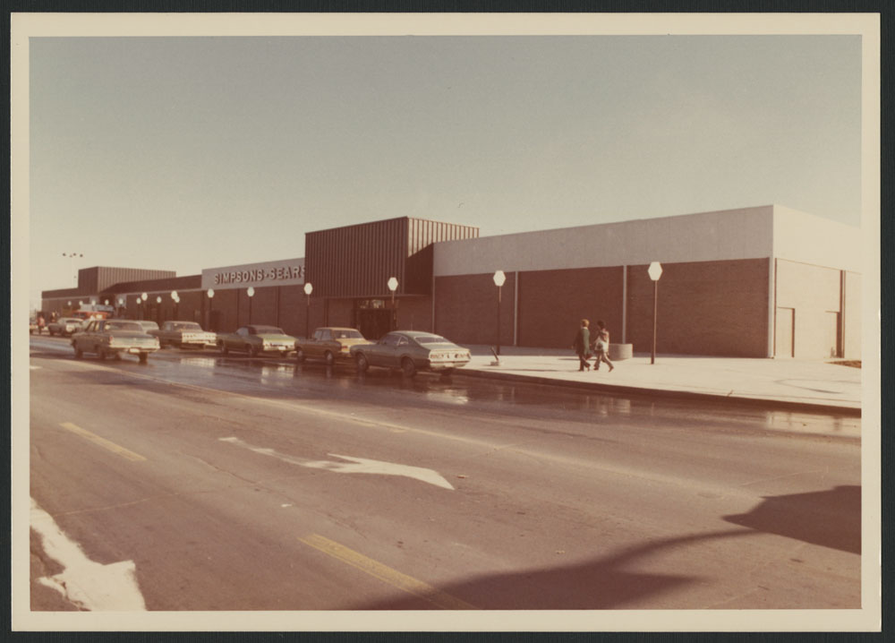 Photos couleur montrant l’extérieur du centre commercial Les Galeries de Hull à Gatineau, au Québec. La photo extérieure montre des voitures stationnées en bordure de la rue, et des gens marchant sur le trottoir; on peut voir « Simpsons-Sears » sur la façade du bâtiment