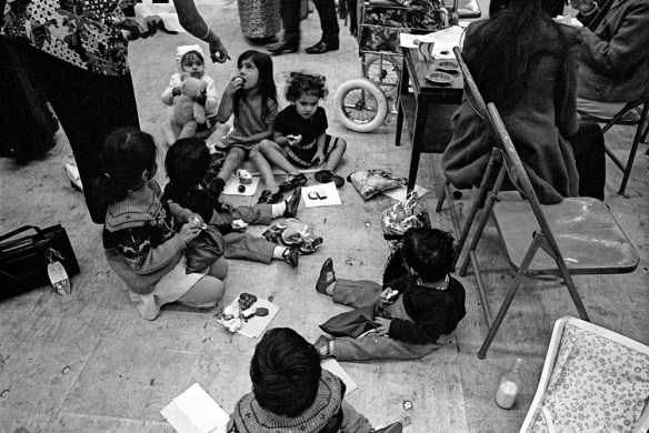 Photographie noir et blanc d’un groupe d’enfants en train de manger par terre.