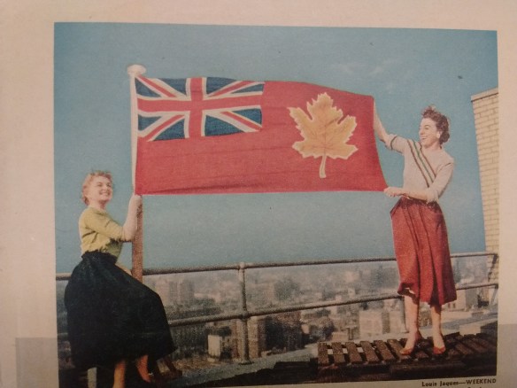 Photographie couleur de deux femmes tenant un drapeau sur le toit d’un édifice.