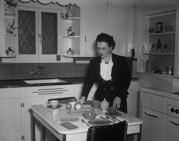 Photo noir et blanc d’une femme mettant la table dans une cuisine