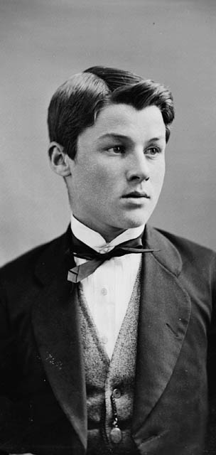 Photo noir et blanc d’un garçon vêtu d’un complet. 