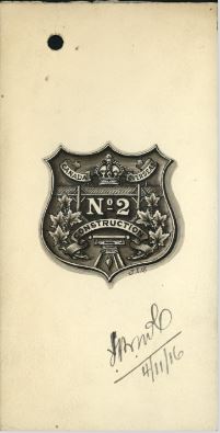 Dessin noir et blanc d’un insigne en forme de bouclier. Au sommet se trouvent une couronne royale et une bannière indiquant « Canada Overseas ». En dessous se trouvent les mots « No. 2 » au-dessus d’une autre bannière avec le mot « Construction ». Des feuilles d’érable ornent les côtés de l’insigne. Un pont en bois sous la couronne et un outil sous la deuxième bannière symbolisent que les membres de l’unité étaient des bâtisseurs. 