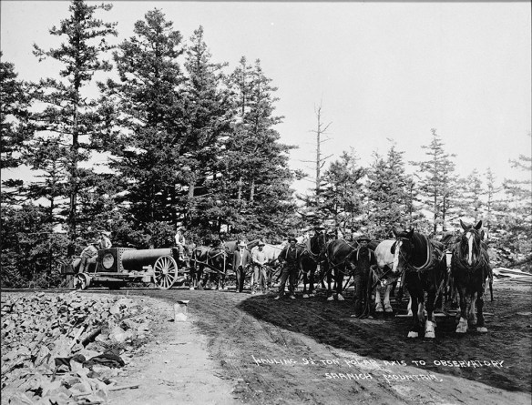 Photographie en noir et blanc d’un groupe d’hommes posant avec un attelage de chevaux attaché à un chariot transportant une partie d’un télescope.