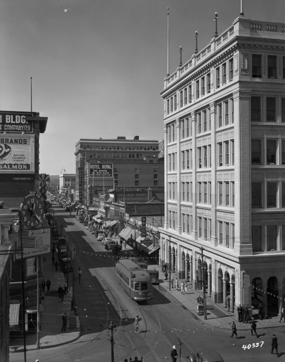 Photo noir et blanc du centre-ville de Calgary. Prise de vue en surplomb d’une intersection où l’on aperçoit des tramways, des voitures et des gens dans les rues et sur les trottoirs.