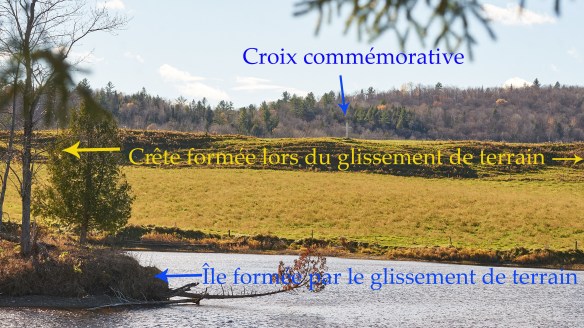 Une croix blanche sur le bord d’une crête. Le terrain en contrebas est nettement moins élevé que la crête.