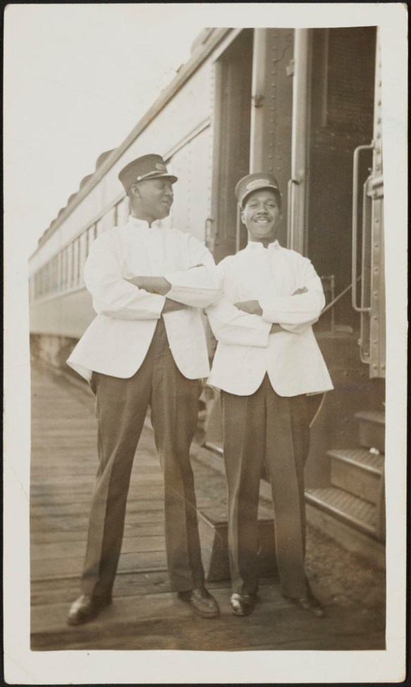 Deux porteurs de voitures-lits du Chemin de fer Canadien Pacifique debout à côté d’un train.
