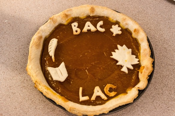 Photo de la tarte qui vient de sortir du four. Des feuilles, une plume, un livre et les mots BAC et LAC en pâte sont posés sur le dessus de la tarte.