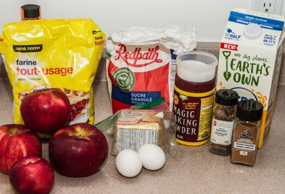 Des pommes, des œufs, du beurre, de la poudre à pâte, du sel, de la farine, du sucre, du lait d’avoine, de la muscade et de la cannelle.