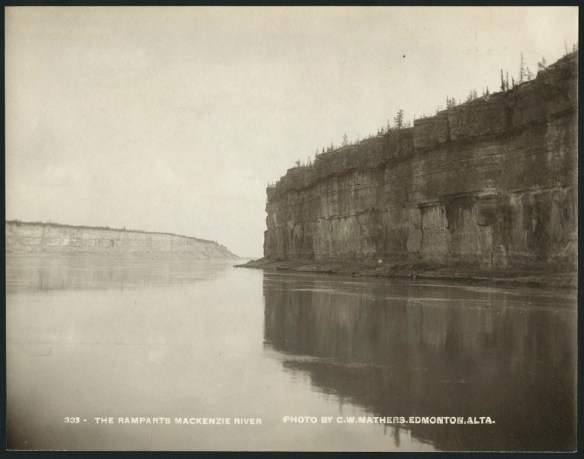 Photographie en noir et blanc de falaises aux parois verticales abruptes sur la rive droite d’un fleuve. La couche supérieure des falaises abrite des arbres et de la végétation. Sur le côté gauche et plus loin à l’horizon se trouve un élément géologique similaire. Le fleuve coule entre les deux.