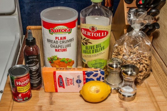 Ingrédients utilisés pour la recette de pain au fromage et aux noix : pâte de tomates, sauce piquante, fromage cheddar, chapelure, huile d’olive, citron, poivre, sel et noix. (L’oignon ne figure pas sur la photo.)