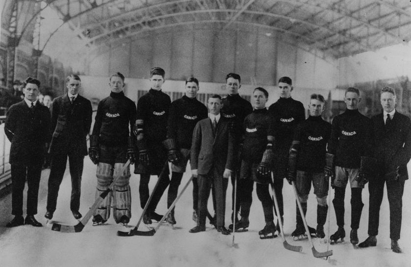 Photographie en noir et blanc d’une équipe de hockey masculine tenant des bâtons de hockey, debout sur la glace.