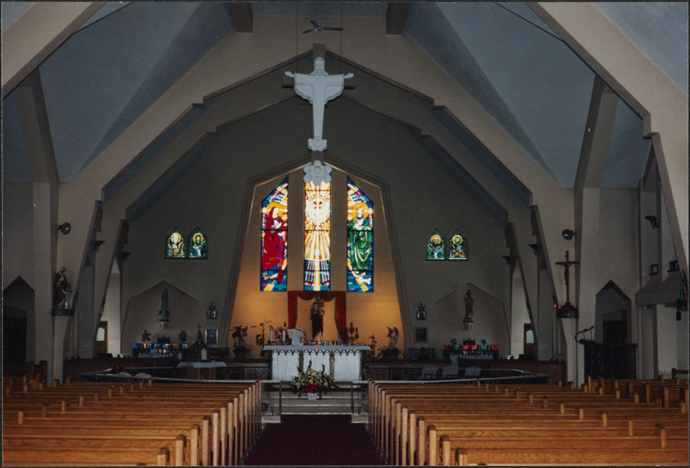 Photo de l’intérieur de la cathédrale Saint-Joseph. On peut voir en avant-plan les bancs de l’église, puis le chœur de l’église, et en arrière-plan, les vitraux sur le mur arrière.