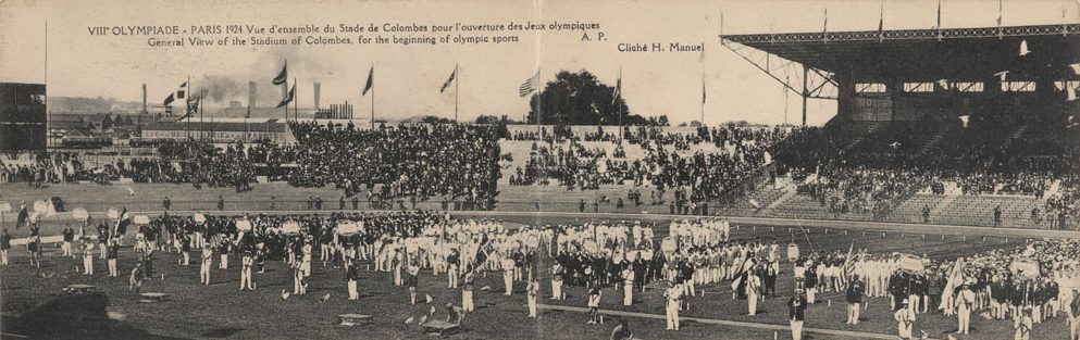Photographie panoramique en noir et blanc d’un stade extérieur dans lequel se trouvent des centaines d’athlètes.