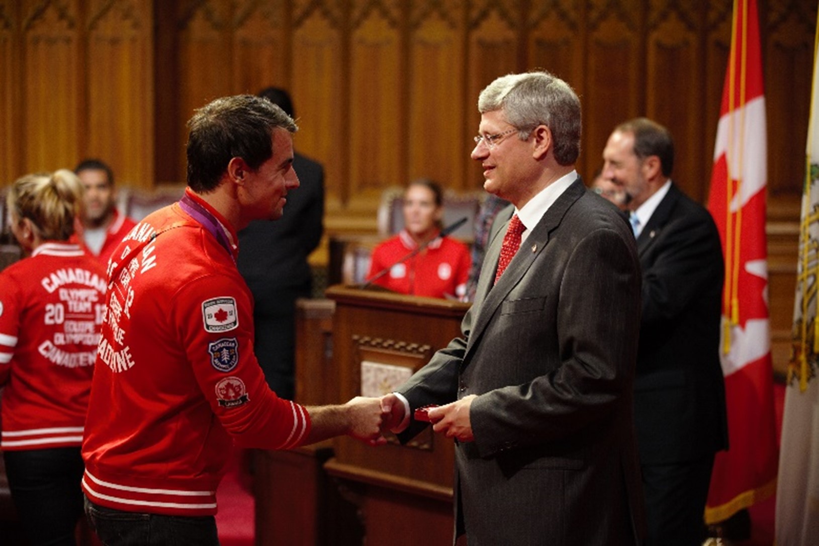 Photographie de deux hommes qui sourient en se serrant la main.